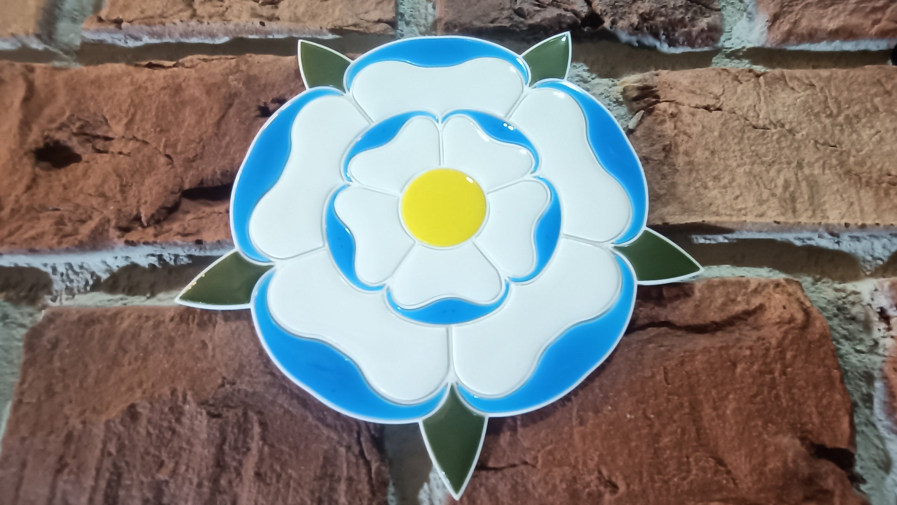 Decorative 3D printed Yorkshire White Rose design with resin detail on a brick wall